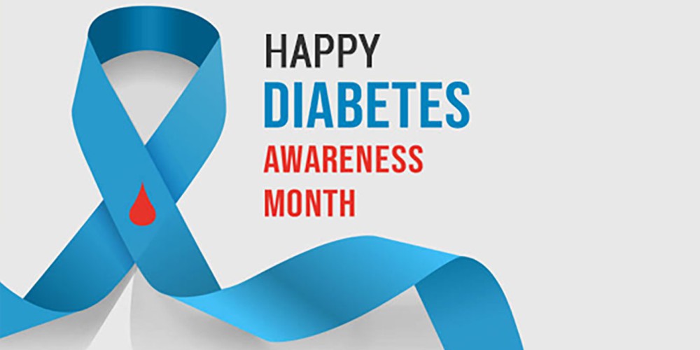 A blue ribbon carries the emblem of a red blood drop, serving as a symbol for Diabetes Awareness Month