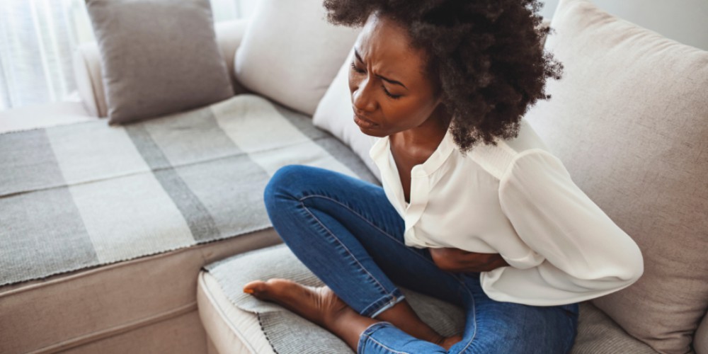 A woman on the sofa in pain emphasizes the importance of paid menstrual leave